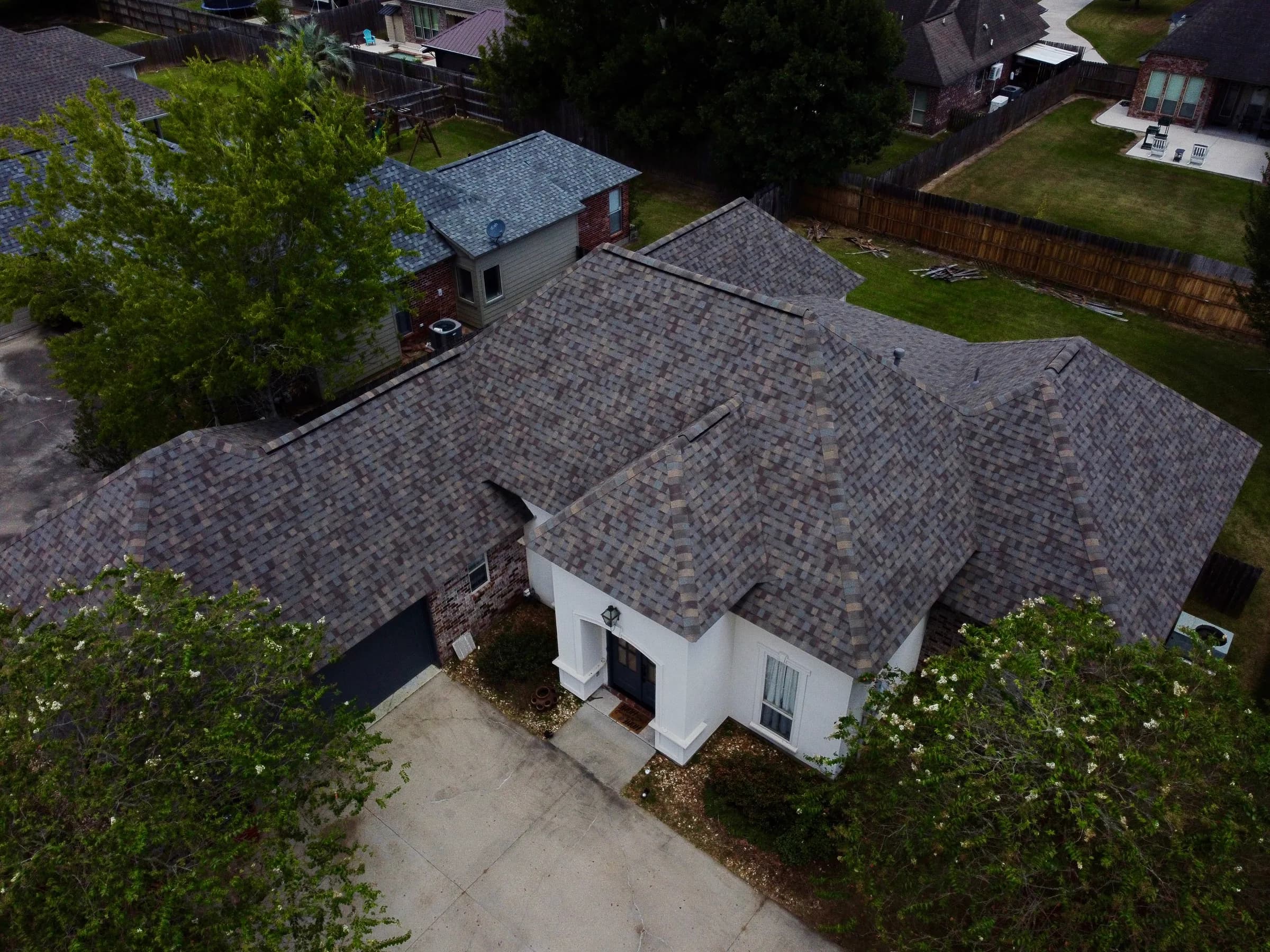 White brick home with new architectural shingle roof after replacement